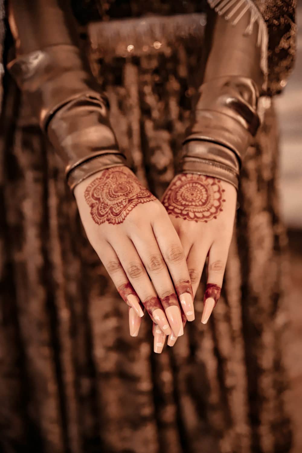 Hands decorated with intricate mehndi and bangles