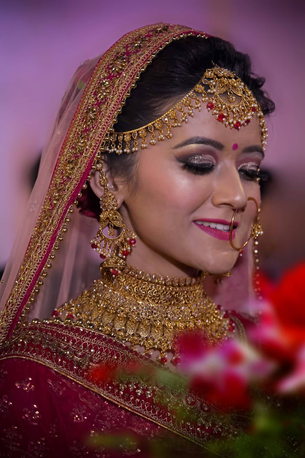 A bride in red and gold with soft, glowing bridal makeup