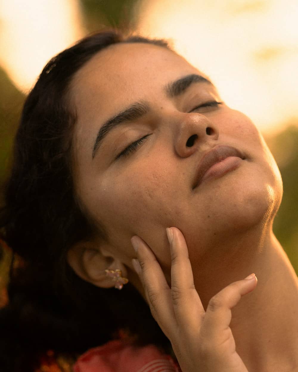 A woman with fresh, glowing skin, eyes closed